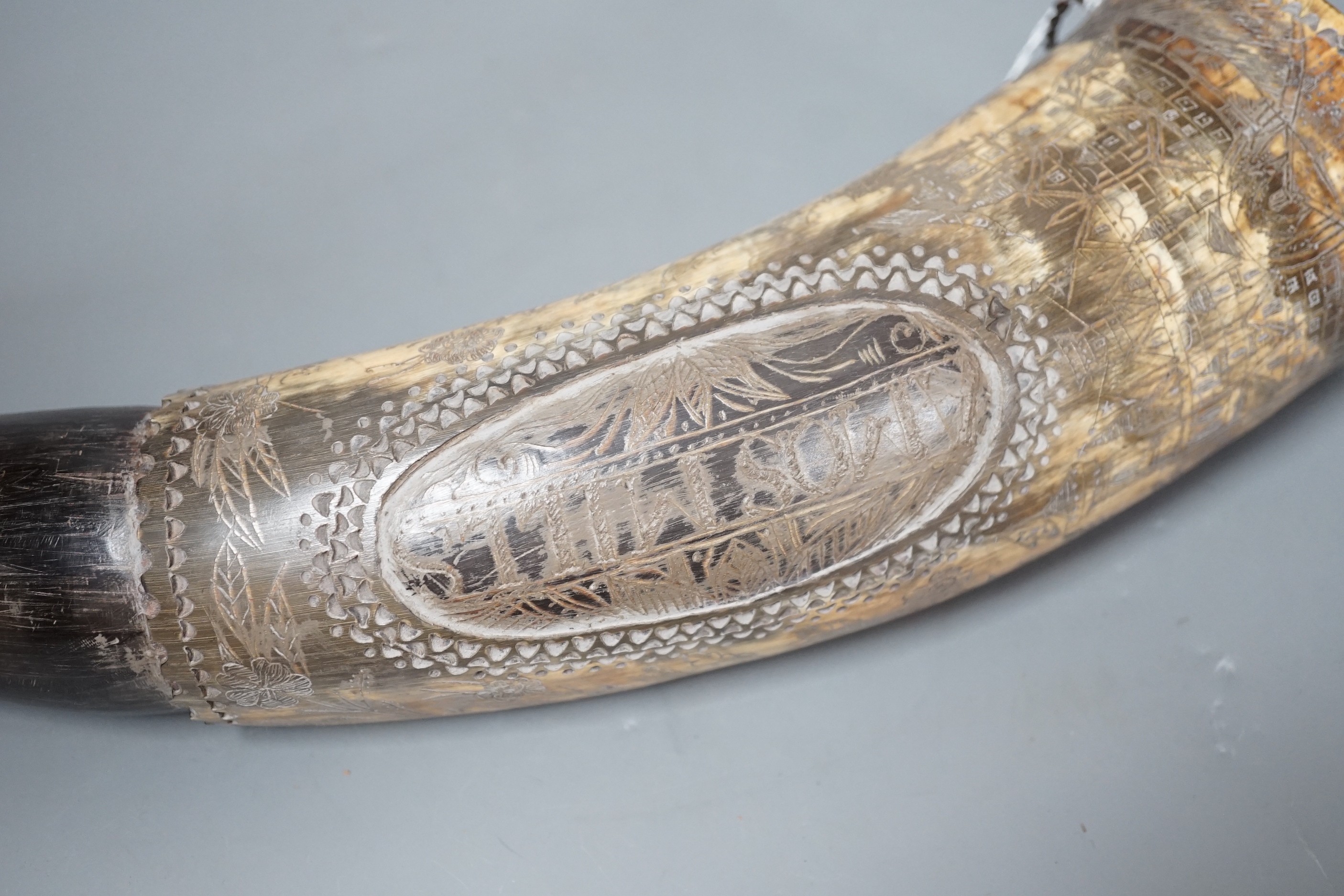 An early 19th century scrimshaw powder horn, ornately engraved with the Royal Coat of Arms, a castle and galleon and an inscription: Amos Mills. 38cms long.